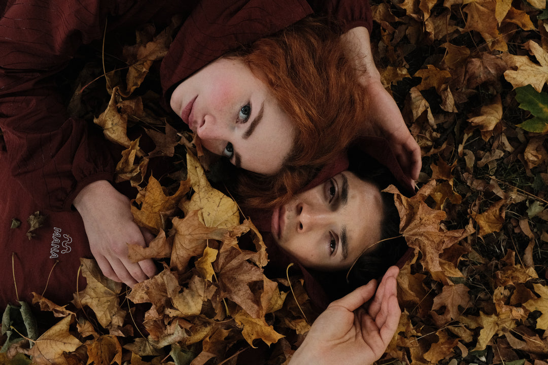 Two people lying on a bed of autumn leaves